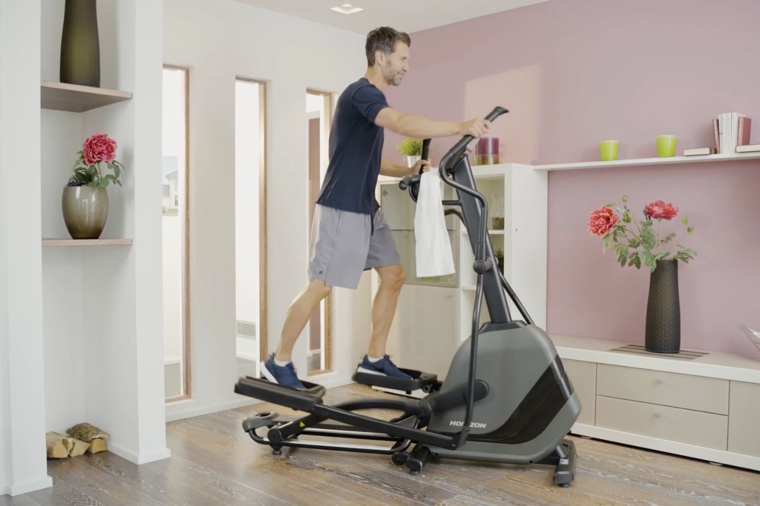 Muž v obývačke cvičiaci na trenažéri Horizon Andes 5.1