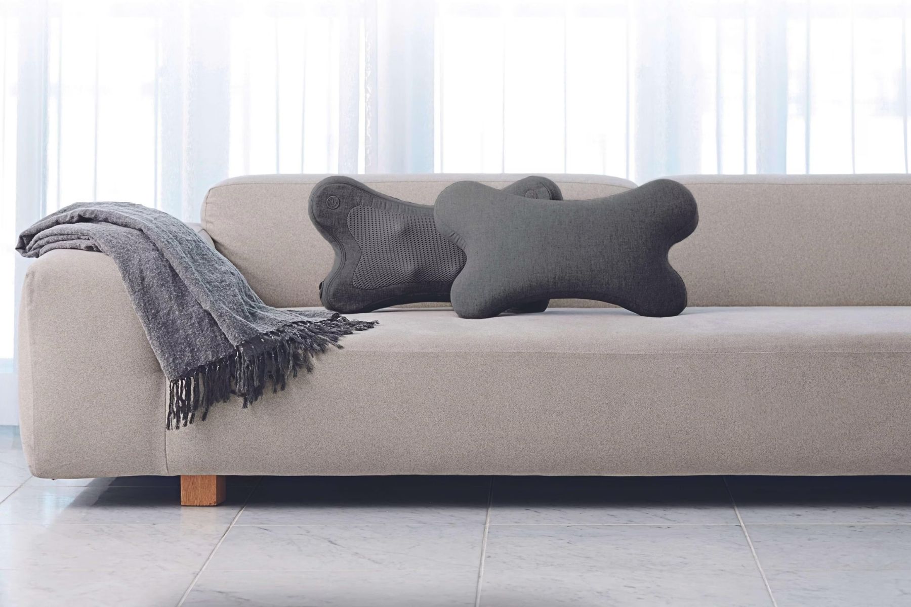 Dva bezdrôtové masážne vankúše Synca iPuffy v elegantnom minimalistickom dizajne na pohovke